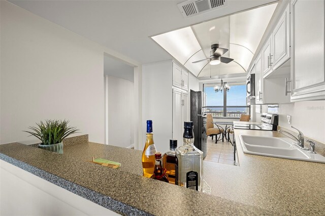 kitchen with stainless steel appliances, visible vents, white cabinetry, a sink, and ceiling fan with notable chandelier