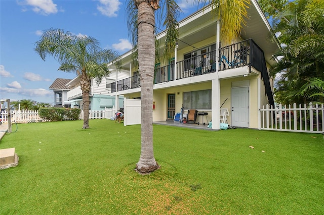 back of property featuring a balcony and a lawn