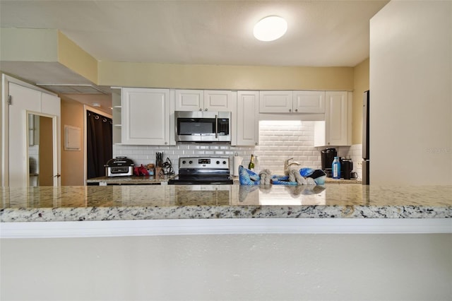 kitchen featuring white cabinetry, light stone counters, decorative backsplash, and stainless steel appliances