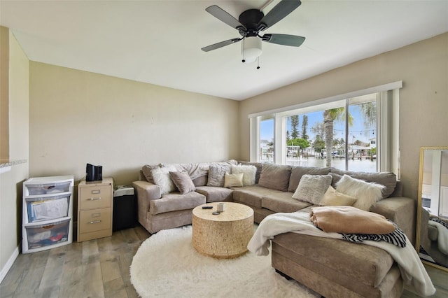 living room with hardwood / wood-style flooring, ceiling fan, and a water view