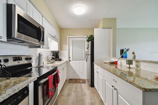 kitchen featuring sink, stainless steel appliances, white cabinets, and light stone countertops