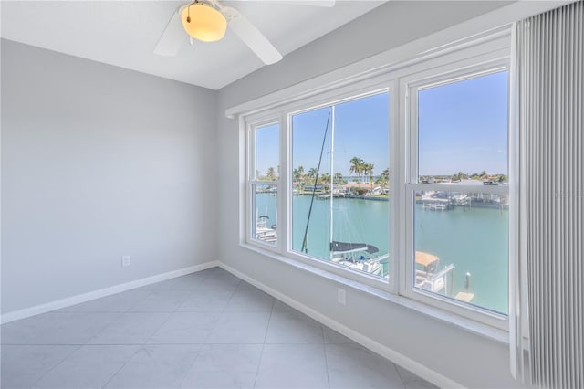 spare room with a water view, ceiling fan, and light tile flooring