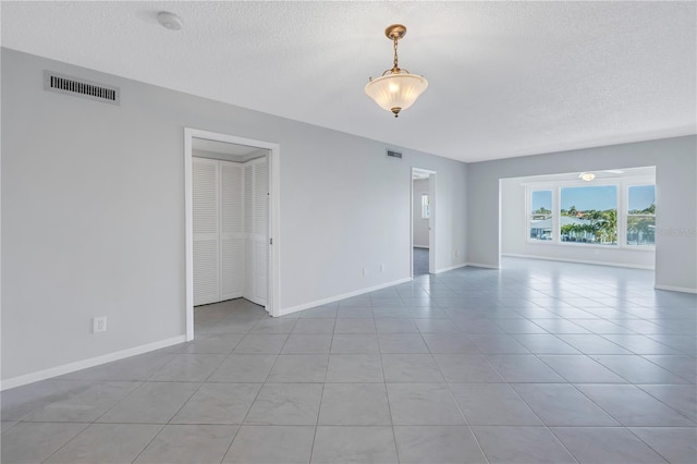 unfurnished room with a textured ceiling and light tile floors