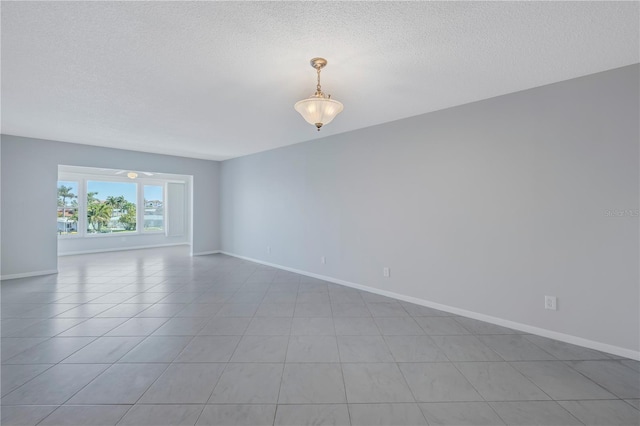 spare room with a textured ceiling and light tile floors