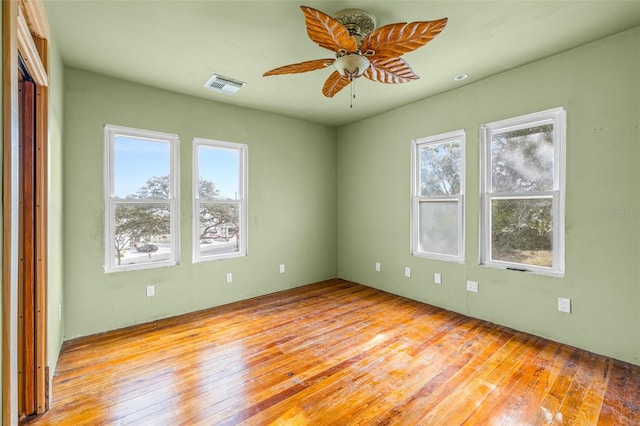 empty room featuring ceiling fan, a healthy amount of sunlight, and light hardwood / wood-style flooring