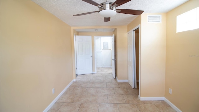 corridor with a textured ceiling and light tile patterned floors