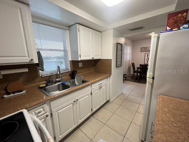 kitchen with light tile patterned flooring, sink, white cabinetry, white appliances, and decorative backsplash