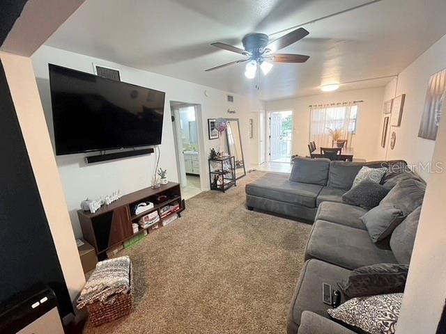 living area featuring a ceiling fan and carpet flooring