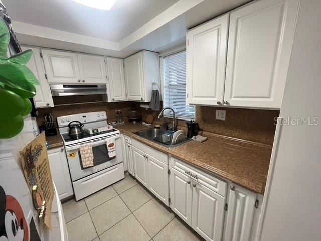 kitchen with under cabinet range hood, a sink, white cabinets, white range with electric cooktop, and dark countertops