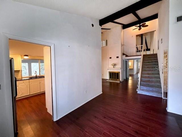 interior space with dark hardwood / wood-style flooring, sink, beamed ceiling, and ceiling fan