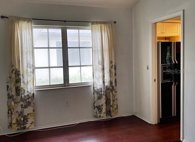 empty room with dark hardwood / wood-style floors and a wealth of natural light