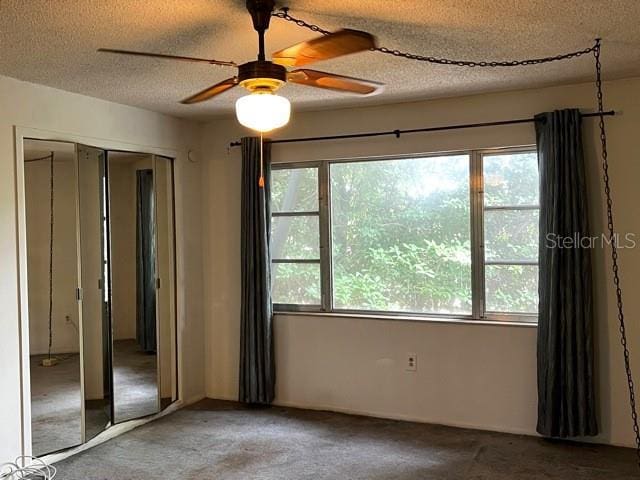 unfurnished room with carpet, a healthy amount of sunlight, and a textured ceiling