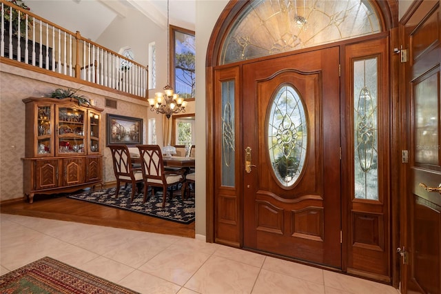 entrance foyer featuring a notable chandelier, light tile floors, and vaulted ceiling