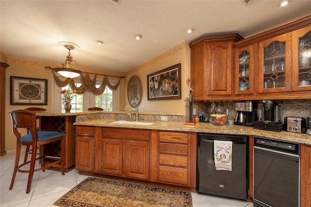 kitchen with pendant lighting, backsplash, dishwashing machine, and light stone counters