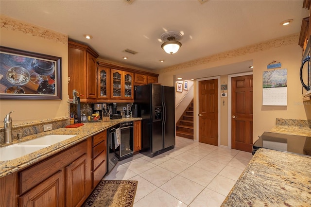 kitchen featuring light tile flooring, sink, black refrigerator with ice dispenser, and light stone counters