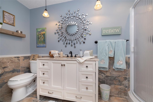 bathroom with toilet, tile flooring, vanity, a textured ceiling, and tile walls