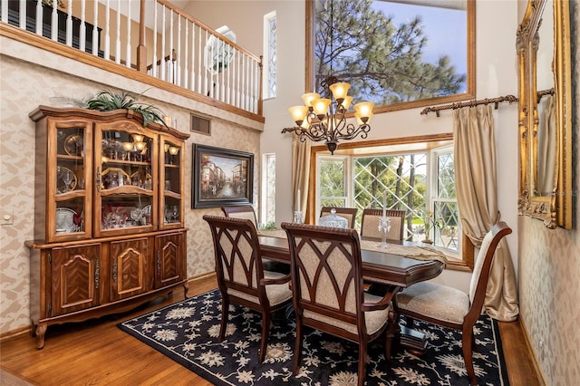 dining area with dark wood-type flooring, a chandelier, and a high ceiling