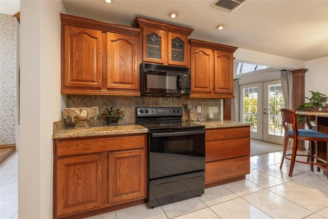 761 Soundview Dr, Palm Harbor, FL 34683 - kitchen with black appliances, french doors, light stone countertops, backsplash, and glass insert cabinets