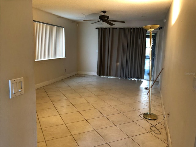 spare room featuring ceiling fan, light tile patterned floors, and a textured ceiling