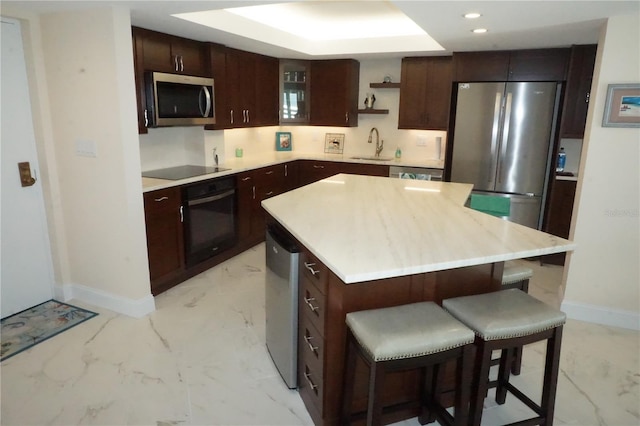 kitchen featuring sink, a center island, dark brown cabinetry, and black appliances