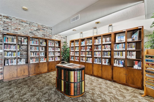 living area featuring a textured ceiling and brick wall