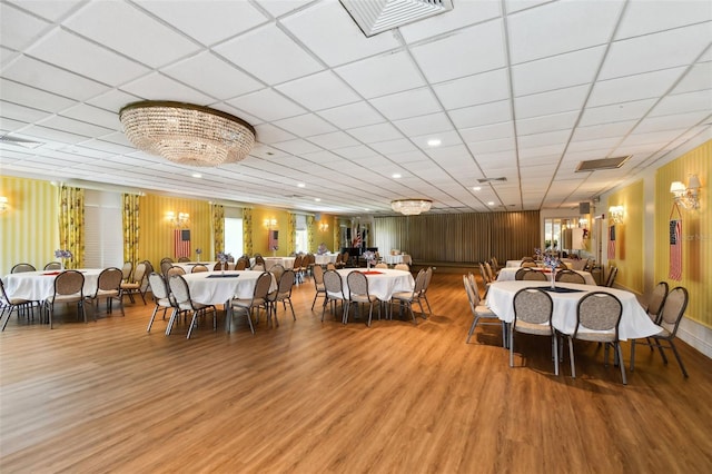 dining space with hardwood / wood-style flooring, a drop ceiling, and an inviting chandelier