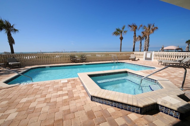 view of pool with a community hot tub, a water view, and a patio