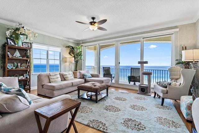 living room featuring a water view, crown molding, wood-type flooring, a textured ceiling, and ceiling fan