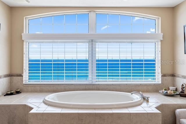 bathroom featuring tiled tub and a healthy amount of sunlight