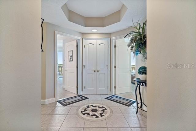 foyer with a raised ceiling and light tile patterned floors