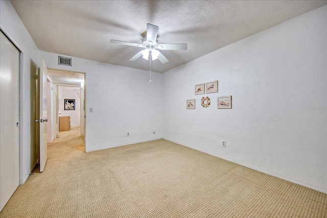 empty room featuring a textured ceiling, ceiling fan, and light carpet