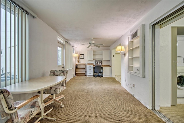 dining room with light carpet, ceiling fan, and stacked washer and clothes dryer