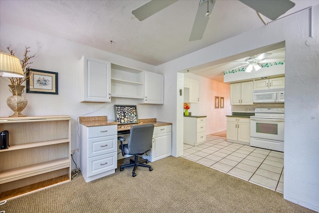 carpeted office space with built in desk and ceiling fan