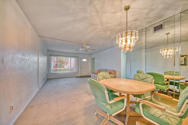 dining area with ceiling fan with notable chandelier and light colored carpet