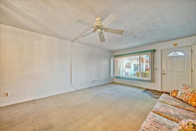 unfurnished living room with a textured ceiling, ceiling fan, and light carpet