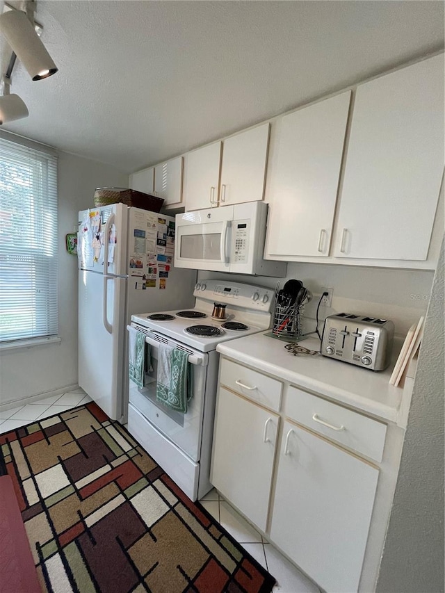 kitchen with white cabinetry, white appliances, a textured ceiling, and tile patterned flooring