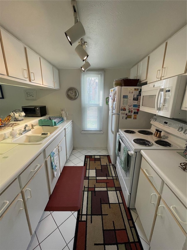 kitchen with white appliances, white cabinets, a textured ceiling, sink, and light tile patterned flooring