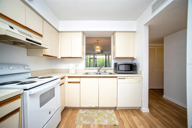 kitchen with light wood-type flooring, a textured ceiling, white appliances, and sink