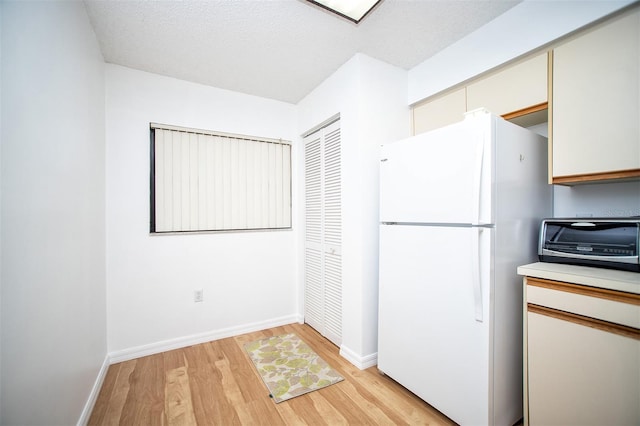 kitchen featuring a textured ceiling, light hardwood / wood-style floors, and white fridge