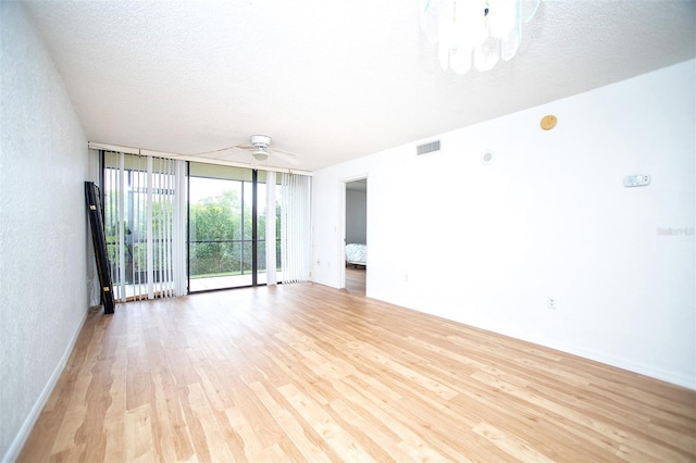 spare room featuring ceiling fan, a textured ceiling, light hardwood / wood-style floors, and expansive windows