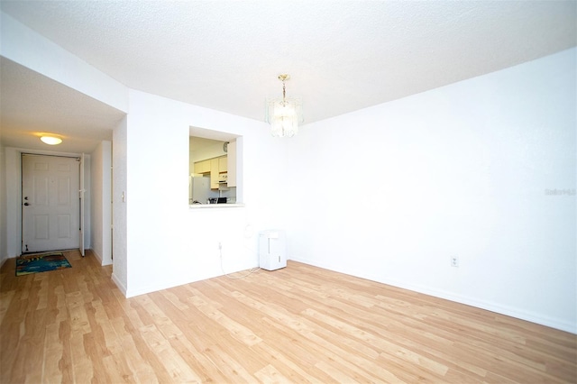 spare room with light wood-type flooring and a textured ceiling