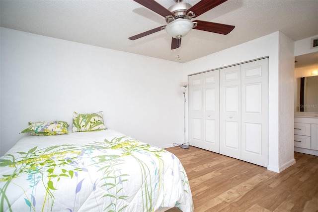 bedroom with ceiling fan, connected bathroom, a textured ceiling, a closet, and light hardwood / wood-style floors