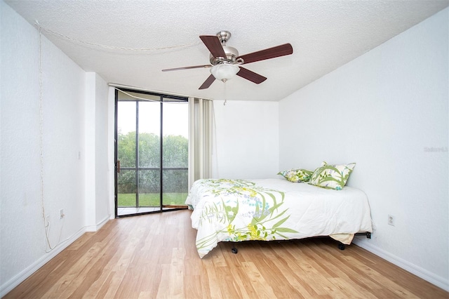 bedroom featuring light hardwood / wood-style floors, a textured ceiling, floor to ceiling windows, access to outside, and ceiling fan