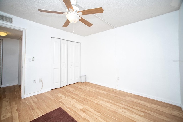 unfurnished bedroom featuring a closet, light wood-type flooring, ceiling fan, and a textured ceiling