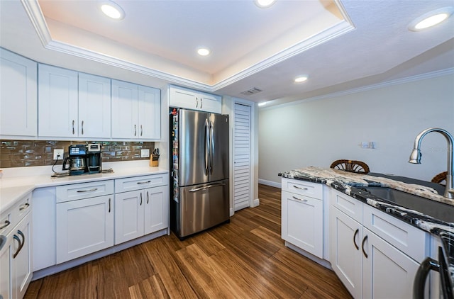 kitchen with white cabinets, a raised ceiling, dark hardwood / wood-style flooring, and stainless steel refrigerator