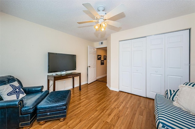 sitting room featuring ceiling fan, a textured ceiling, and light hardwood / wood-style flooring