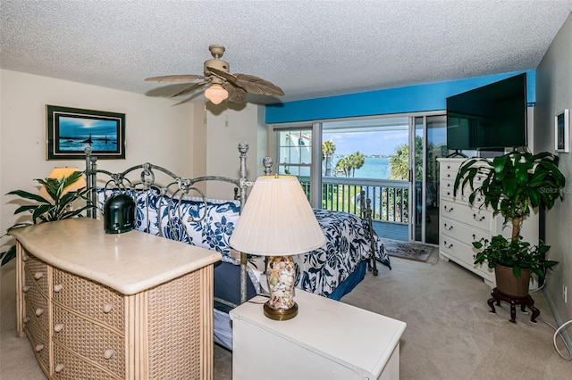 bedroom featuring access to outside, ceiling fan, light carpet, and a textured ceiling