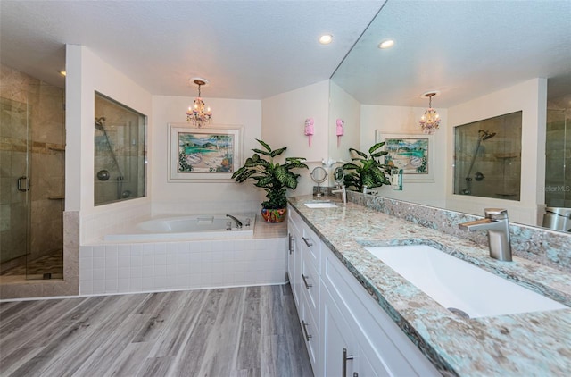 bathroom featuring vanity, plus walk in shower, wood-type flooring, and a notable chandelier