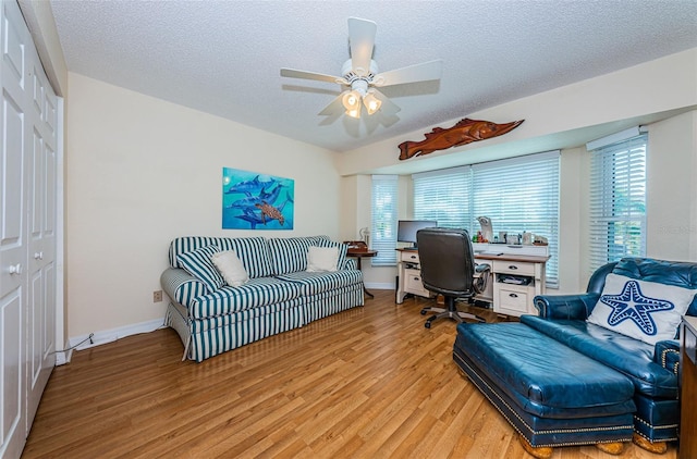 home office featuring baseboards, plenty of natural light, a textured ceiling, and light wood finished floors