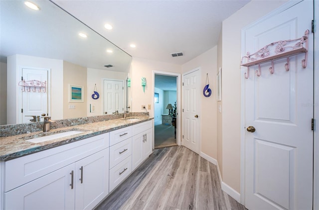 bathroom with double vanity, visible vents, a sink, and wood finished floors